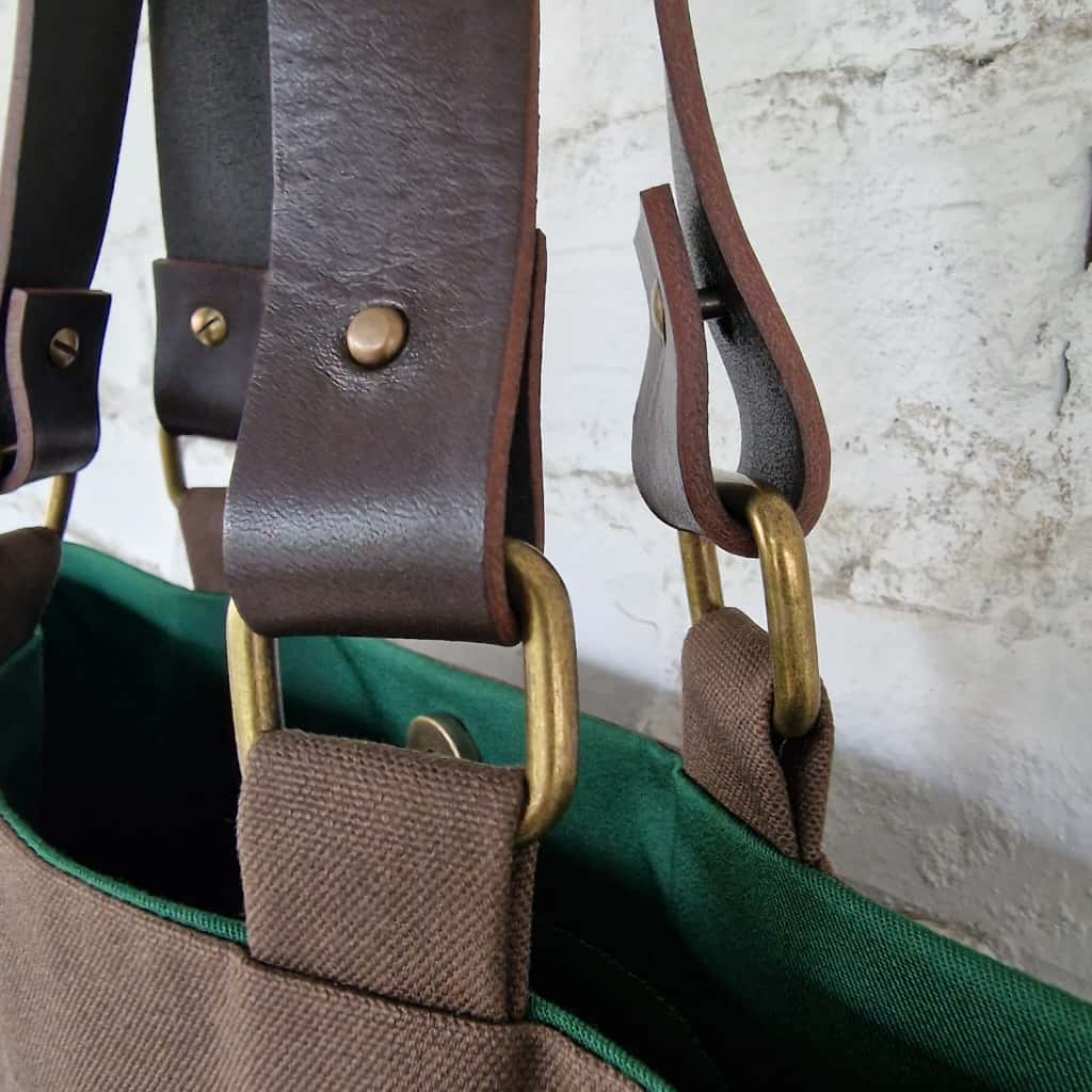 Detailed view of leather straps and brass hardware on handmade dark brown tote bag with green cotton lining by RIMALINUM