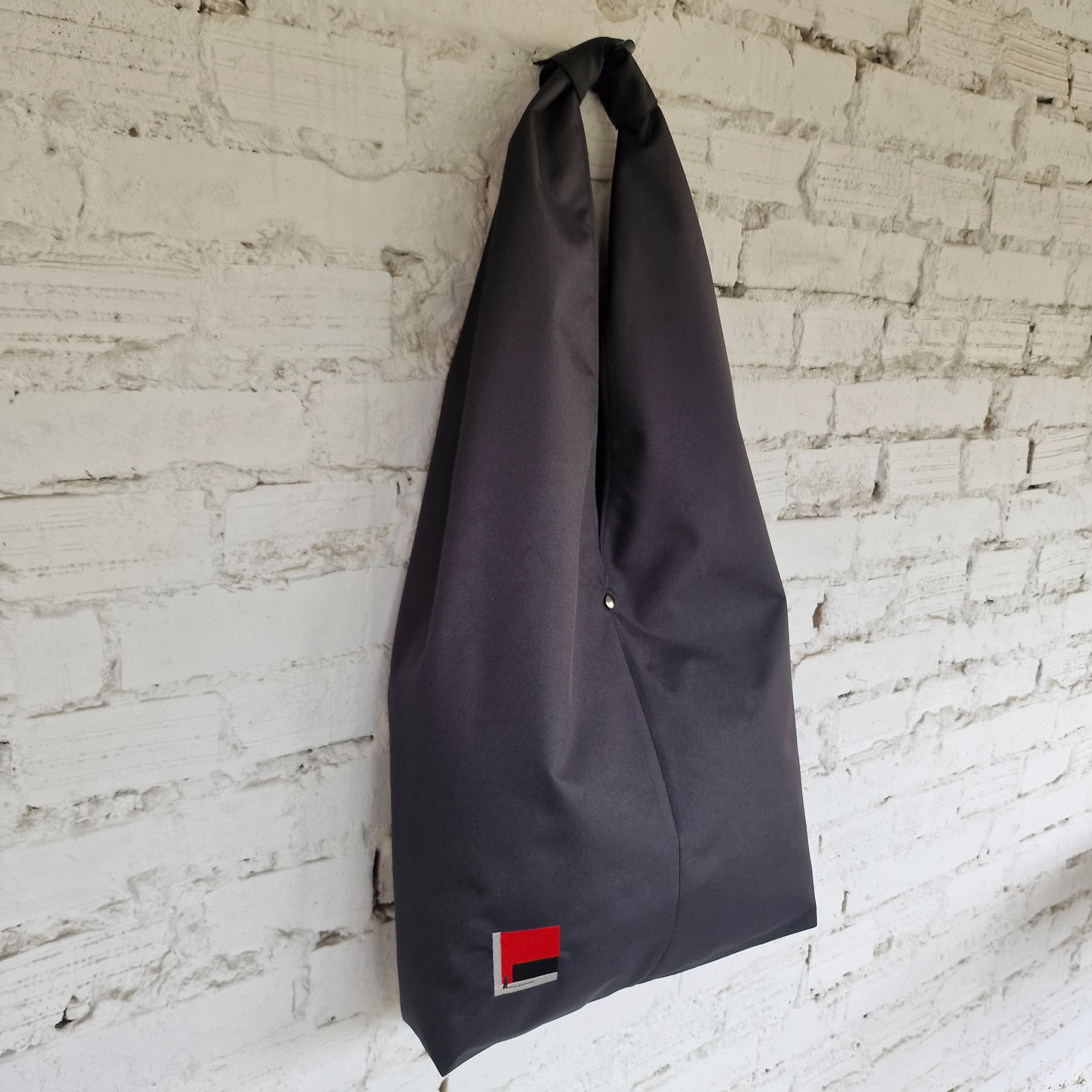 Front view of black HOBO bag with minimalist embroidered design