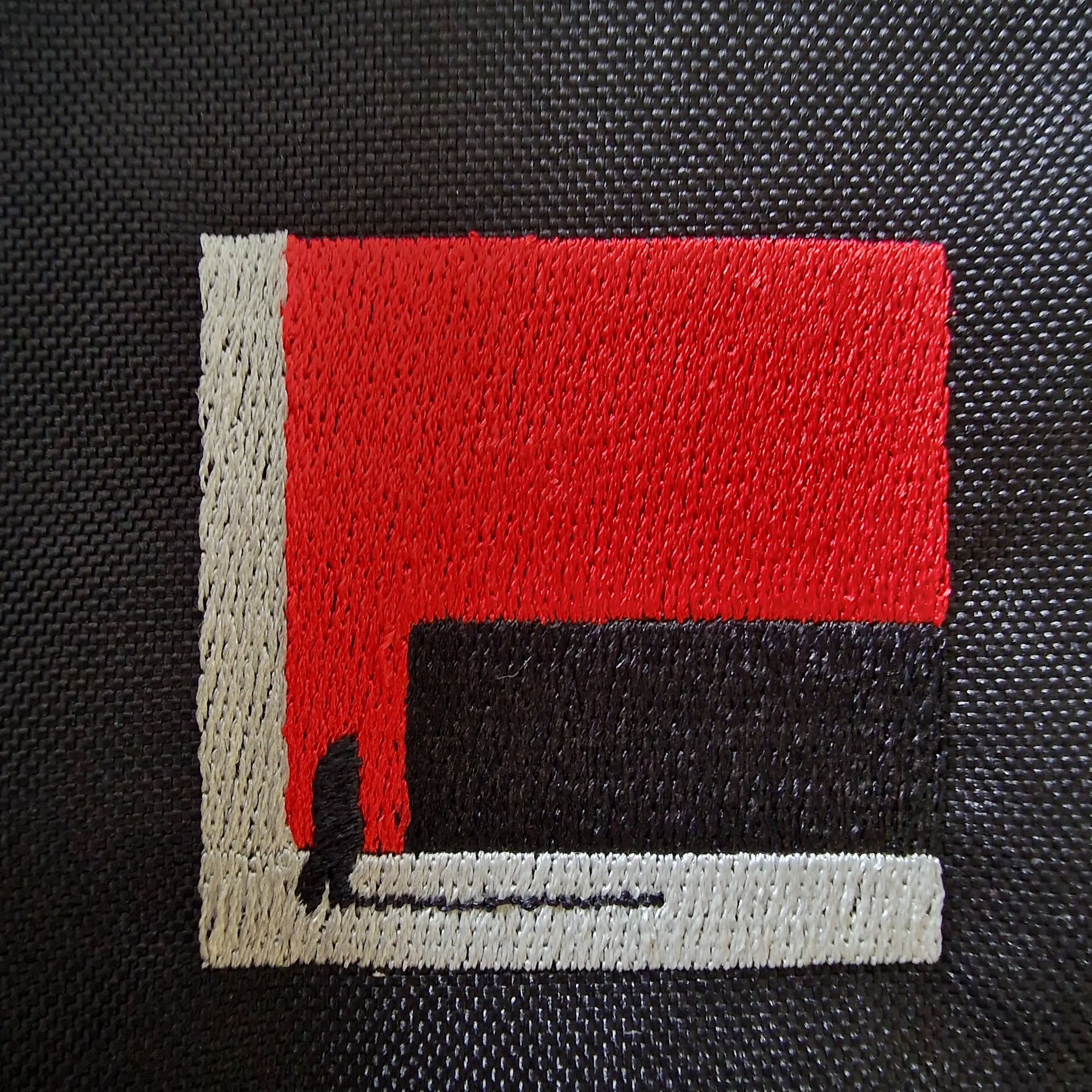 Detailed shot of embroidery design “The Path Finder” on the black shoulder bag