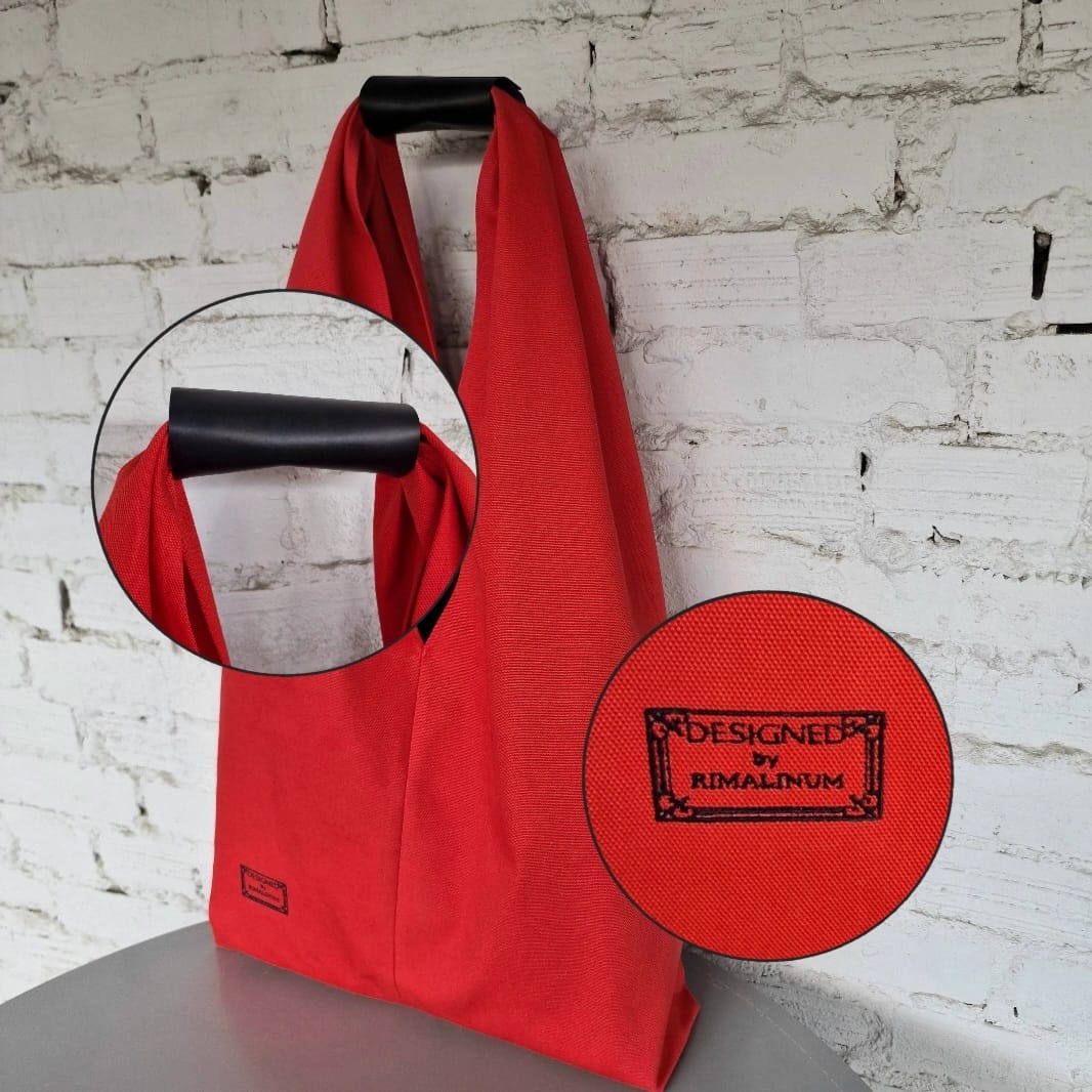 Close-up of Designed by Rimalinum embroidery label on red cotton tote bag