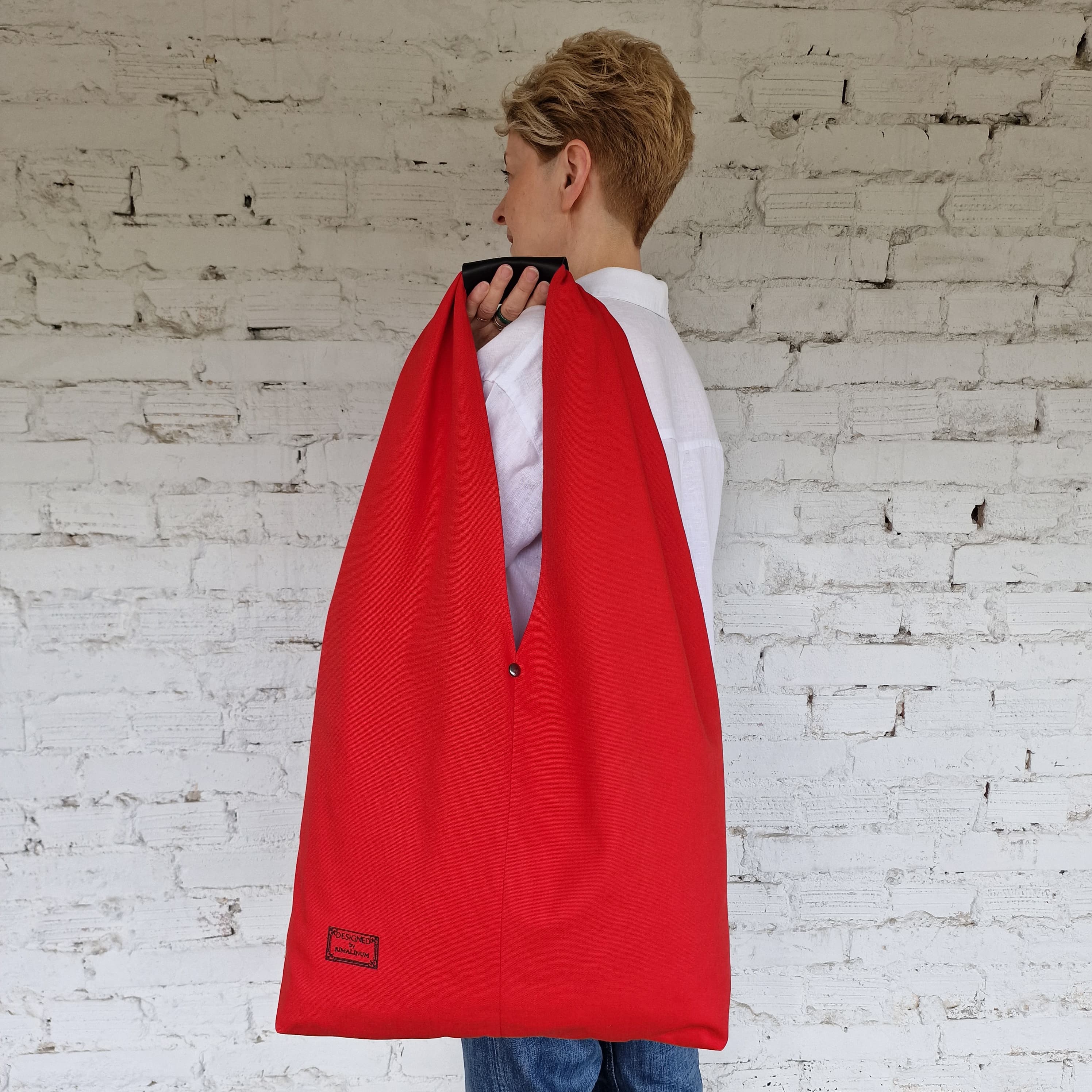 Person wearing a red cape against a white brick wall