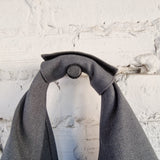 Close-up of tied shoulder strap with snap button closure on modern dark grey linen bag