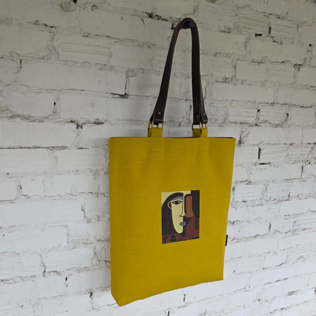 Artistic yellow tote bag with face embroidery and brown lining
