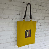 Artistic yellow tote bag with face embroidery and brown lining