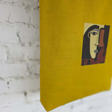 Yellow fabric with an embroidered face design against a marble background