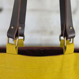 Brown leather handle attachment detail on yellow bag
