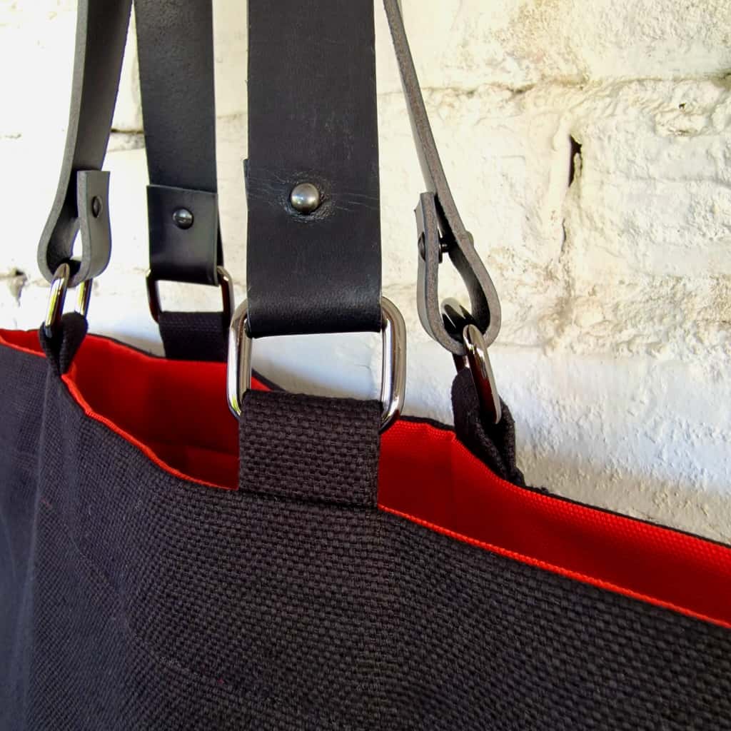Metal hardware and leather strap detail on black linen-cotton tote bag