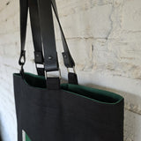 Top view of black linen tote bag with deep green interior lining and leather strap hardware