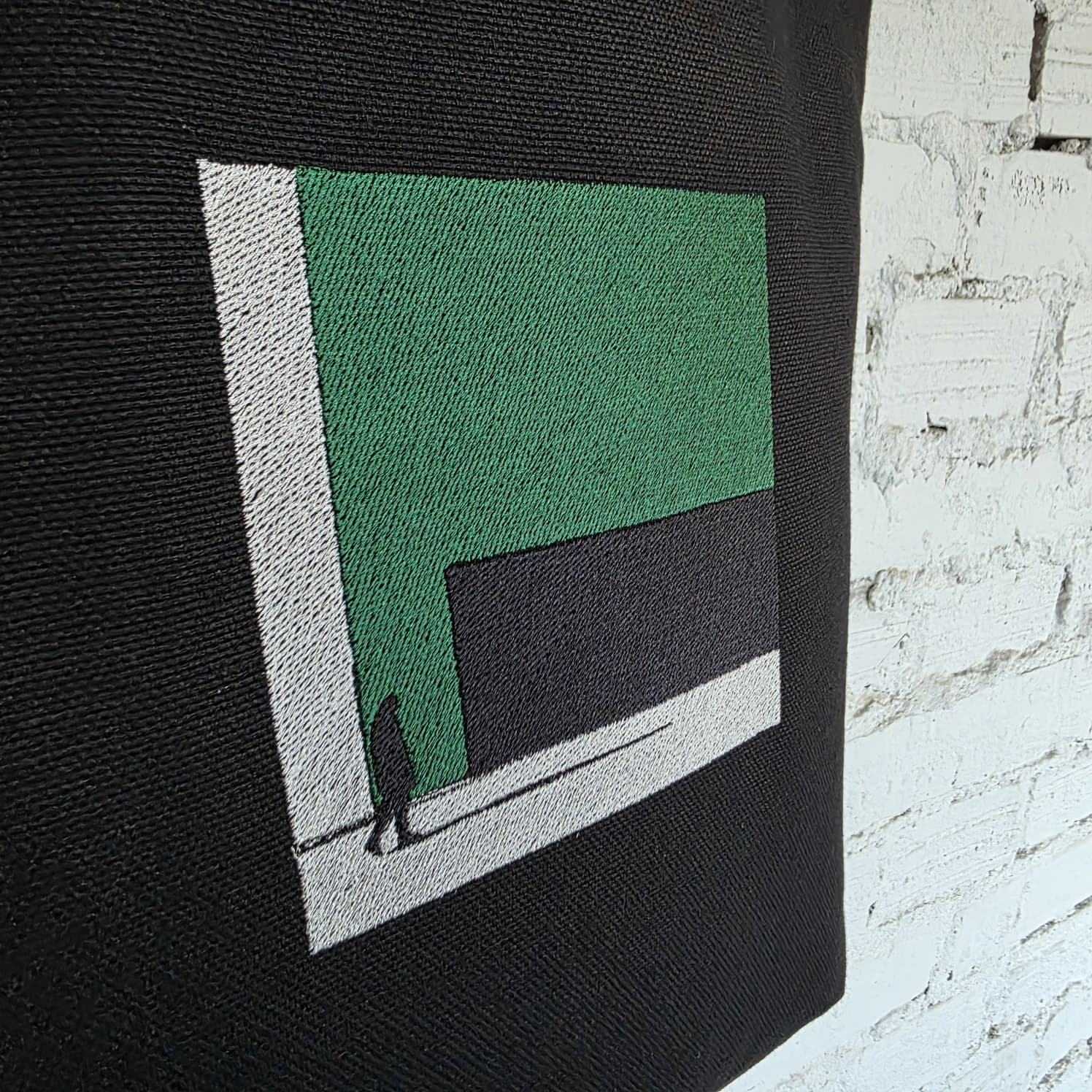 Lower part of the black linen tote showing the embroidered minimal geometric design and fabric texture