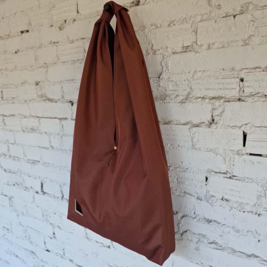 Brown bag hanging against a textured white brick wall