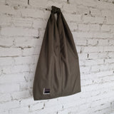 Khaki HOBO bag hanging against a white brick wall