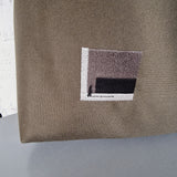Khaki HOBO bag  with a small embroidered design on a gray surface