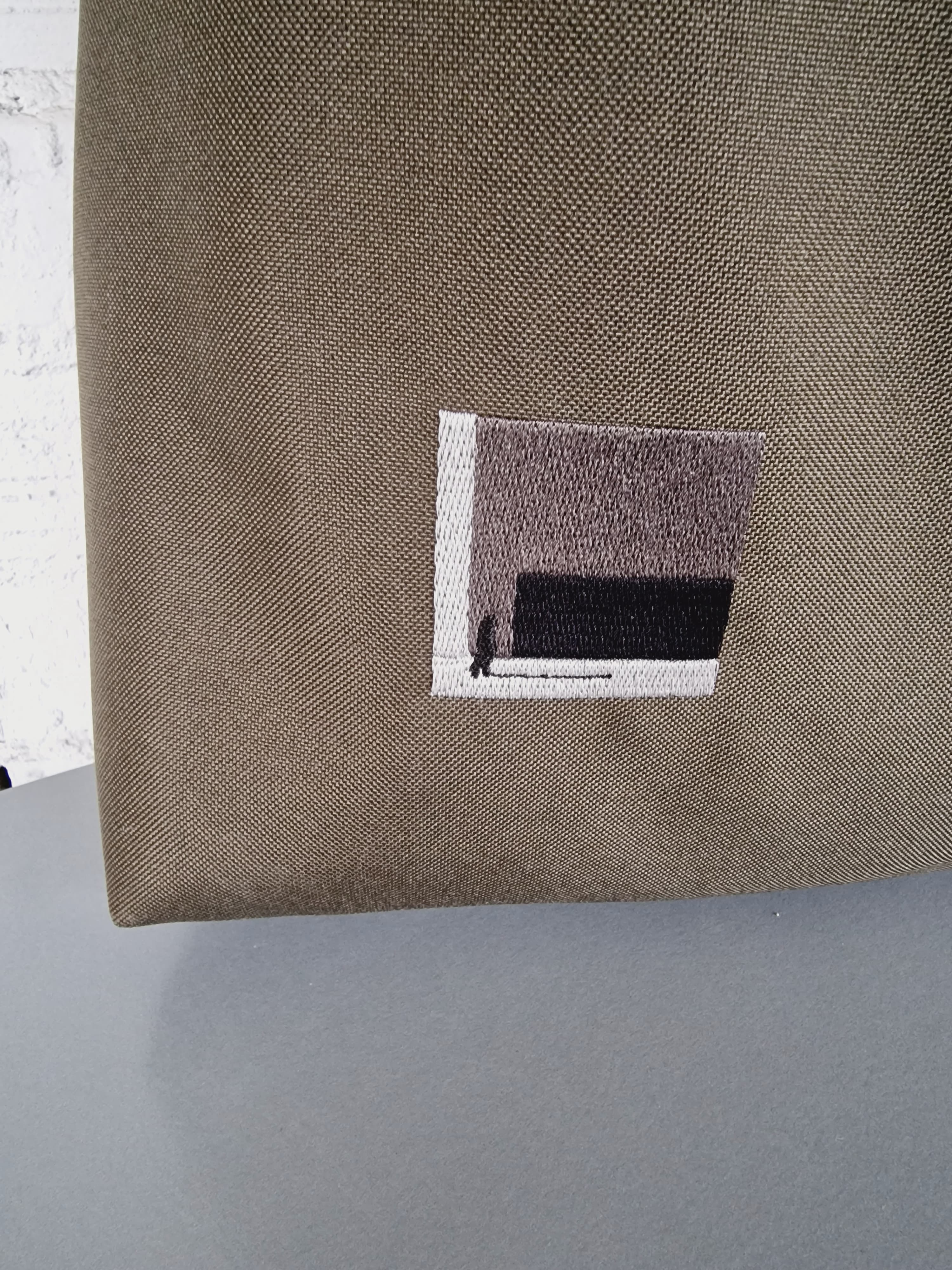 Khaki HOBO bag  with a small embroidered design on a gray surface