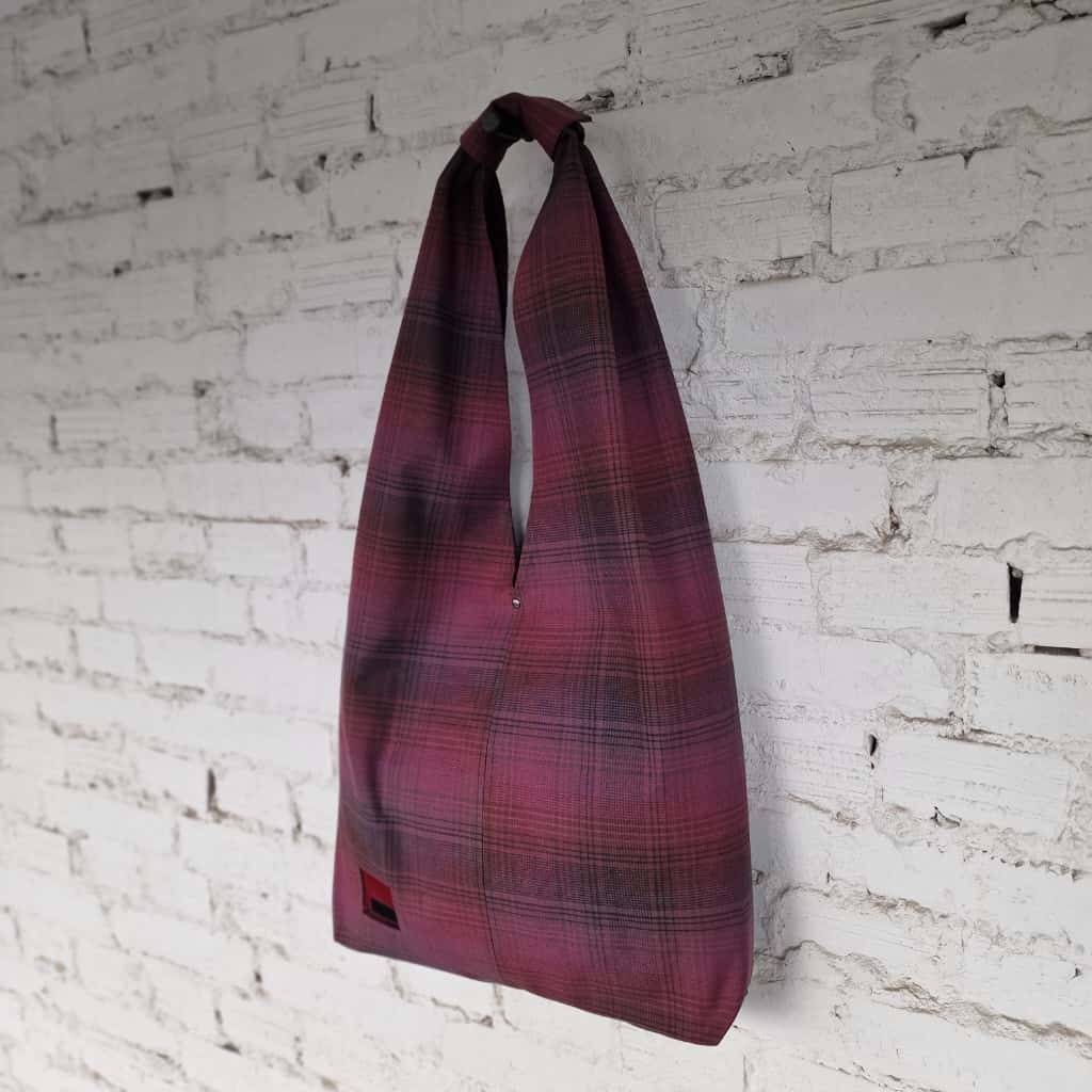 Handmade burgundy plaid cotton hobo bag on white brick wall