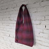 Handmade burgundy plaid cotton hobo bag on white brick wall