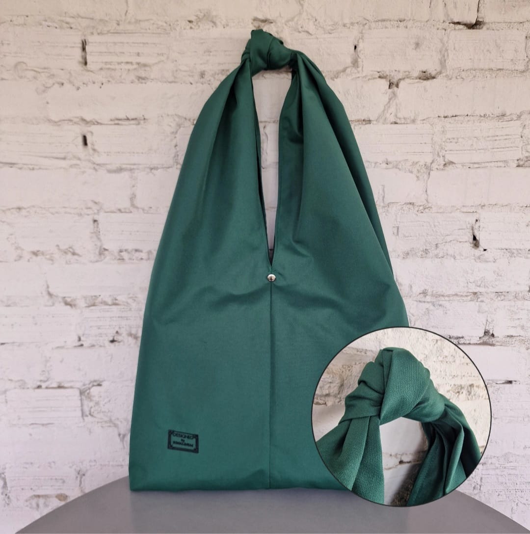 Front view of the minimalist oversized HOBO bag. Shown flat to highlight its clean lines, waterproof fabric, and sculptural knot detail.