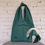 Front view of the minimalist oversized HOBO bag. Shown flat to highlight its clean lines, waterproof fabric, and sculptural knot detail.