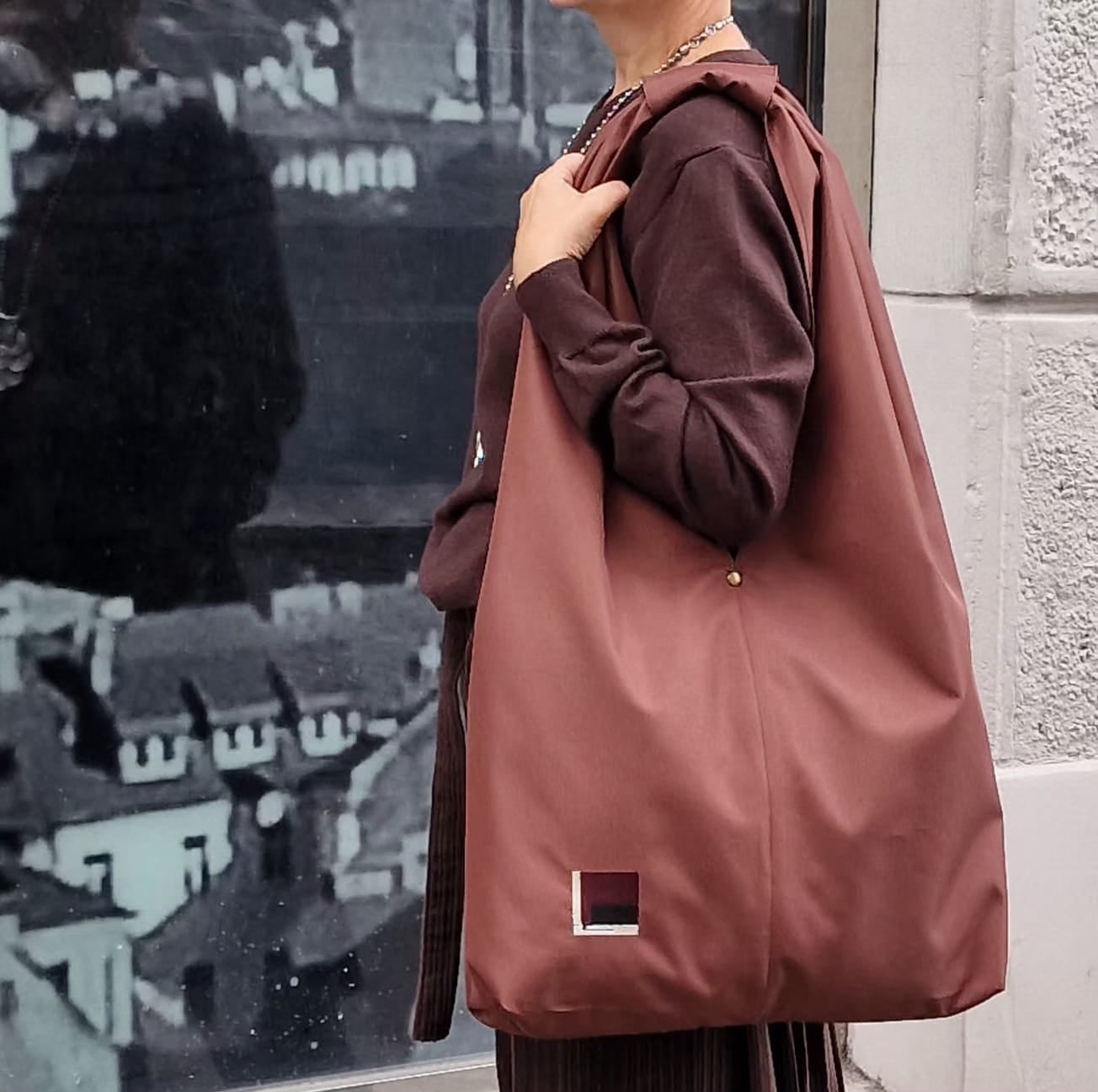 Modern woman wearing dark brown outfit with rust brown hobo bag, casual slow fashion street style