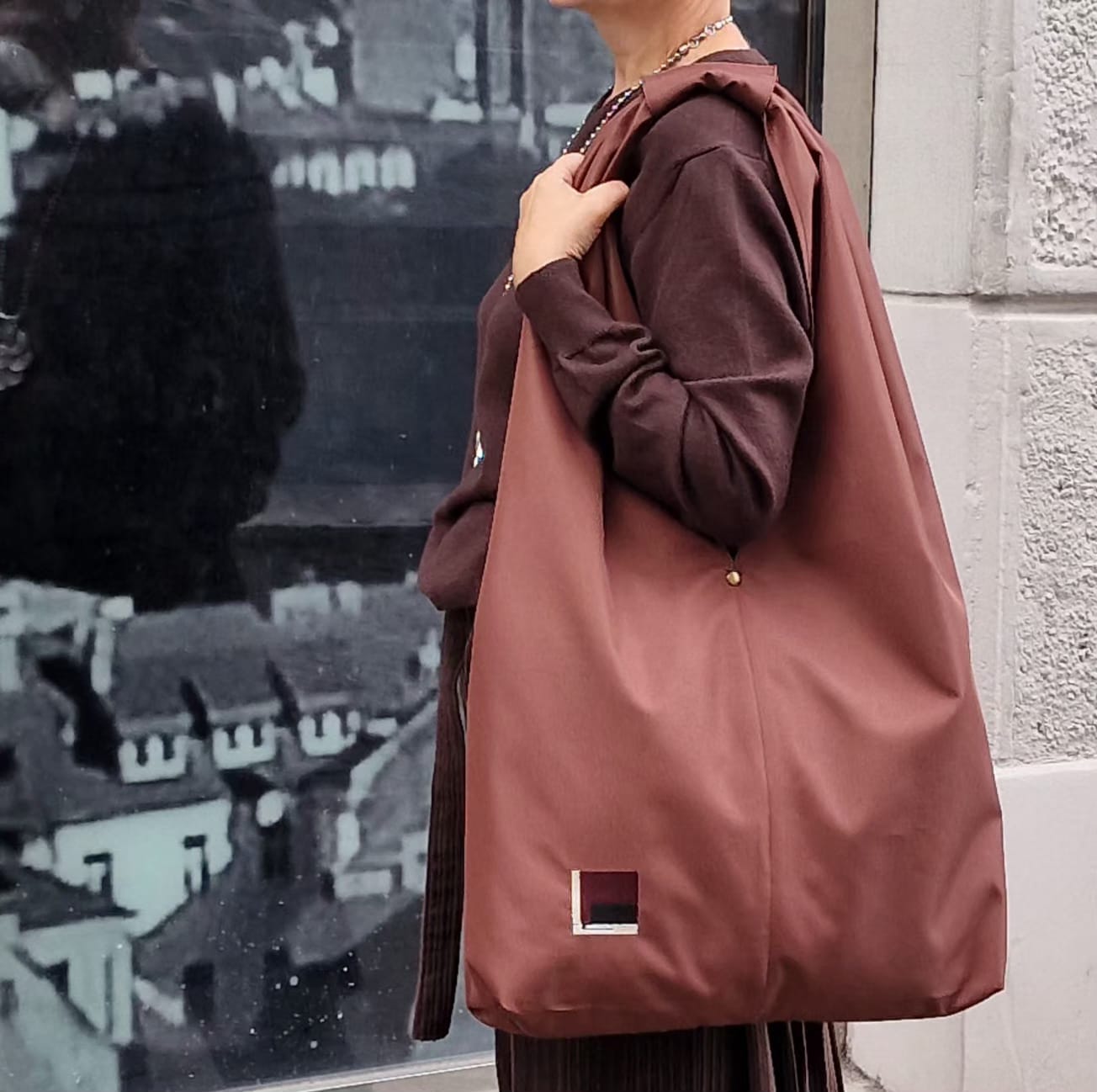 Modern woman wearing dark brown outfit with rust brown hobo bag, casual slow fashion street style