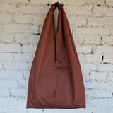 Brown bag with a visible brand logo against a white brick wall