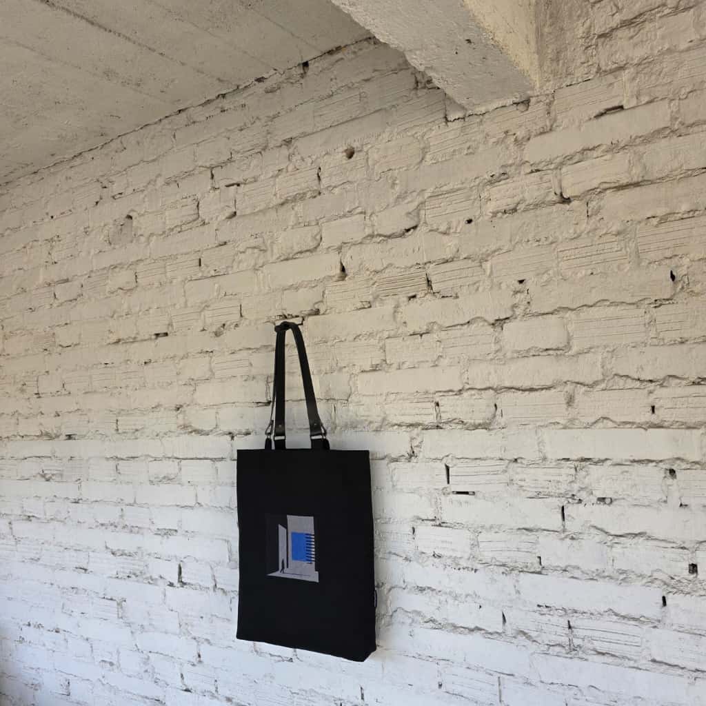 Minimalist black embroidered tote on white brick wall