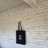 Minimalist black embroidered tote on white brick wall