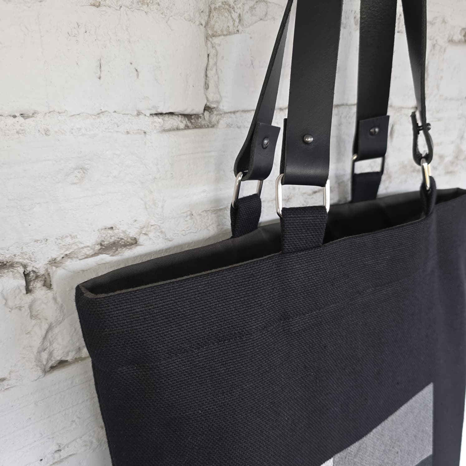 Black tote bag with genuine leather straps and modern minimalist embroidered artwork