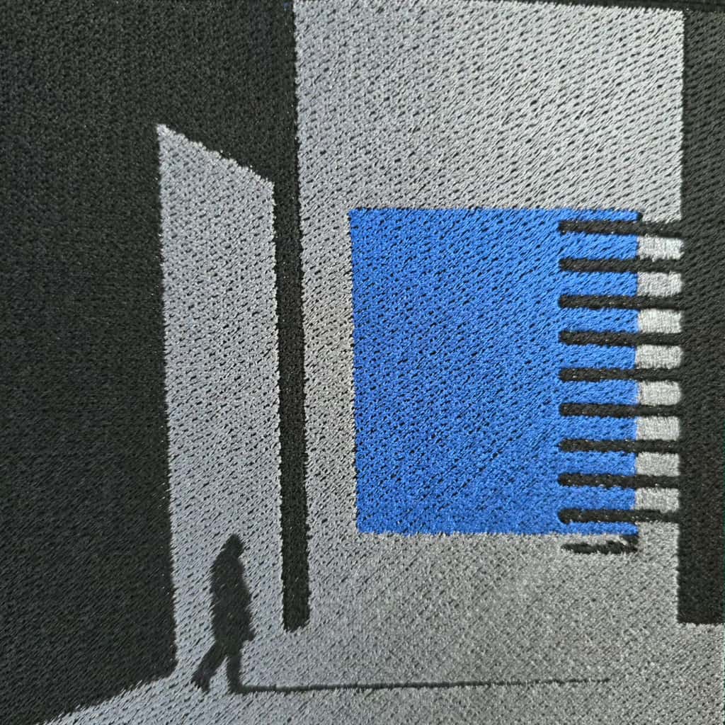 Doormat with geometric design featuring a blue square and black lines on a gray background