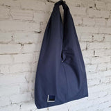 Navy blue bag hanging against a white brick wall