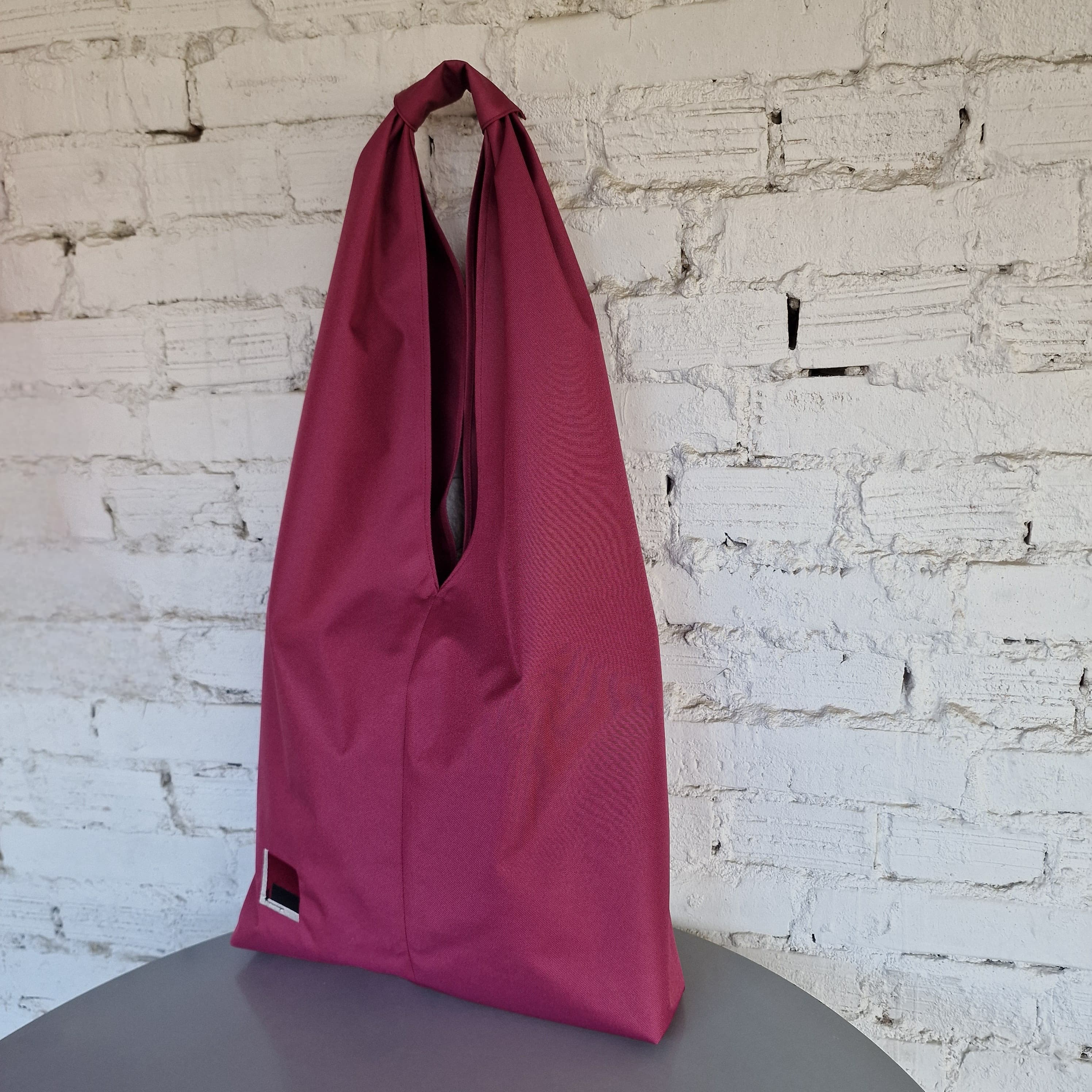Large burgundy hobo bag displayed upright, minimalist water-resistant fabric tote for everyday use