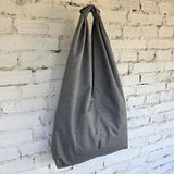 Gray tote bag hanging against a white brick wall