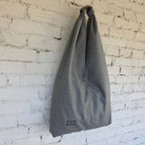 Gray tote bag hanging against a white brick wall