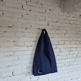 Full view of navy blue hobo bag with small embroidered label and simple clean design