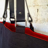Metal hardware and leather strap detail on black linen-cotton tote bag
