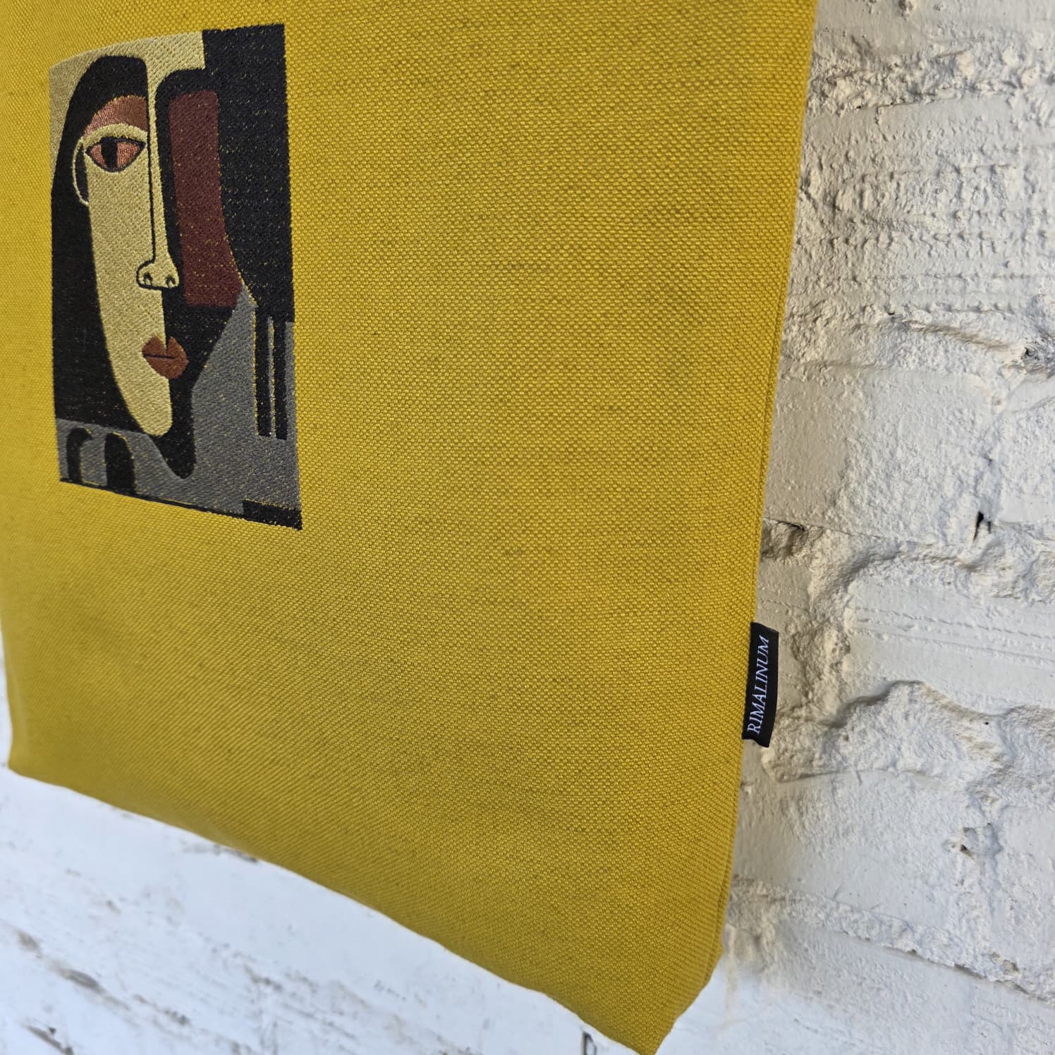 Close-up of abstract face embroidery on mustard canvas