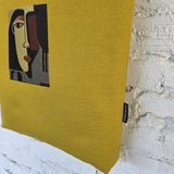 Close-up of abstract face embroidery on mustard canvas