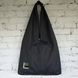 Black bag with a small green label on a white brick wall background