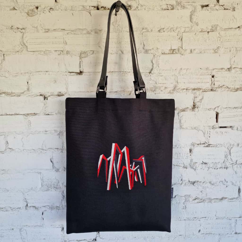 Full view of handmade black linen-cotton tote bag with leather straps and embroidered art motif