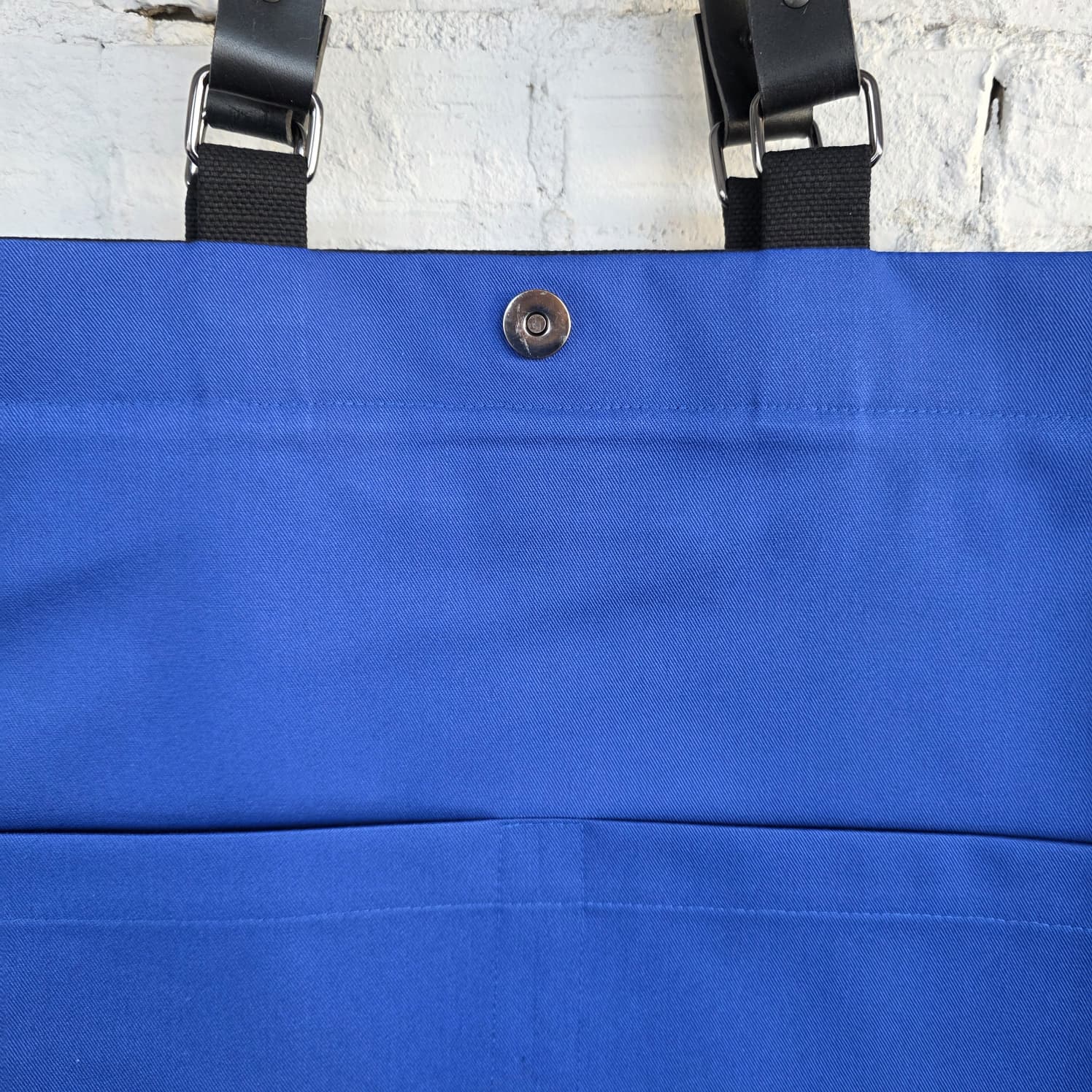 Interior of black canvas tote bag with bright blue lining and magnetic snap closure, spacious handmade laptop and work bag