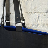 Black canvas tote bag with detachable genuine leather handles and blue lining detail, close-up of durable metal hardware and minimalist handmade construction