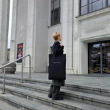 Eco-friendly black tote bag shown outdoors near architecture