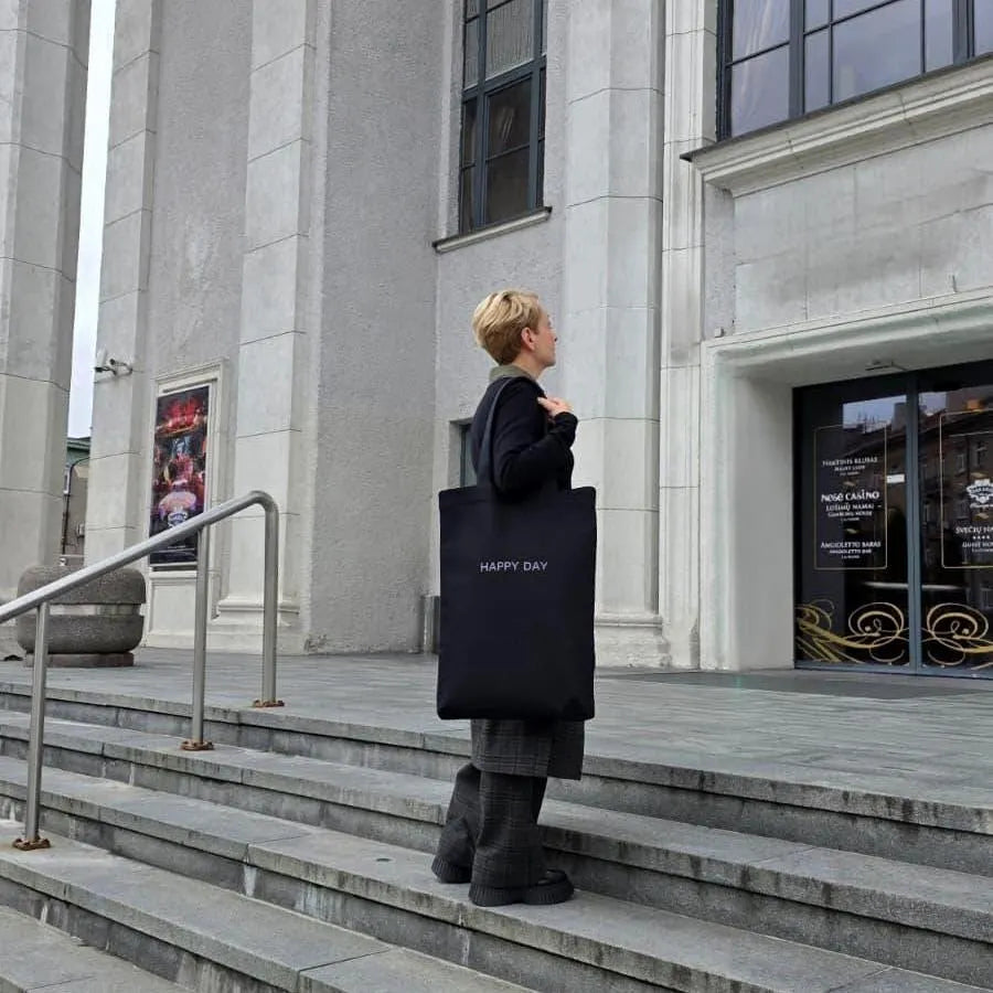 Eco-friendly black tote bag shown outdoors near architecture