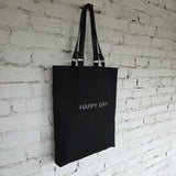Black linen-cotton tote shown flat to display shape, removable leather straps, and clean minimalist construction