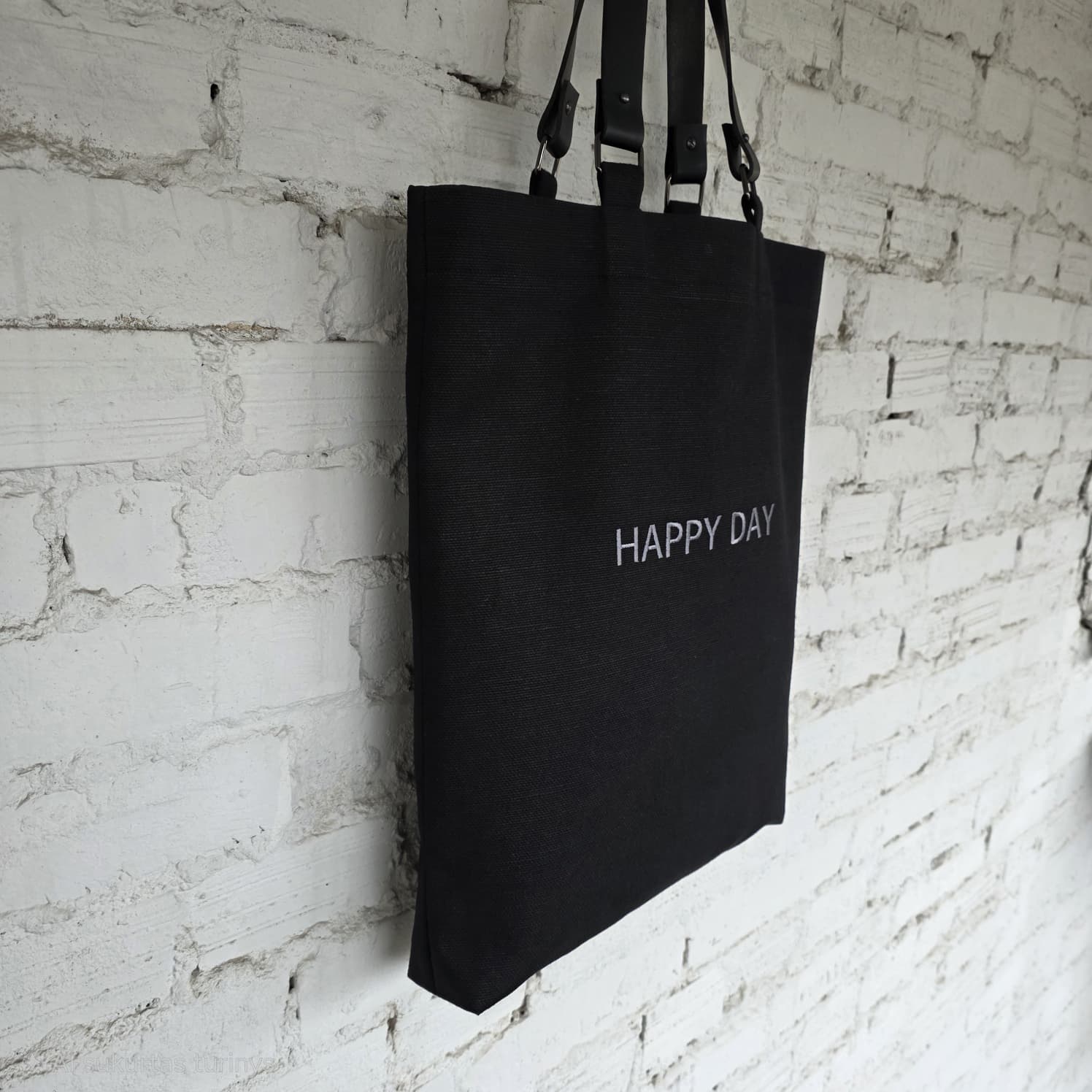 Black linen-cotton tote bag with removable leather handles, embroidered “Happy Day” text, minimalist everyday design