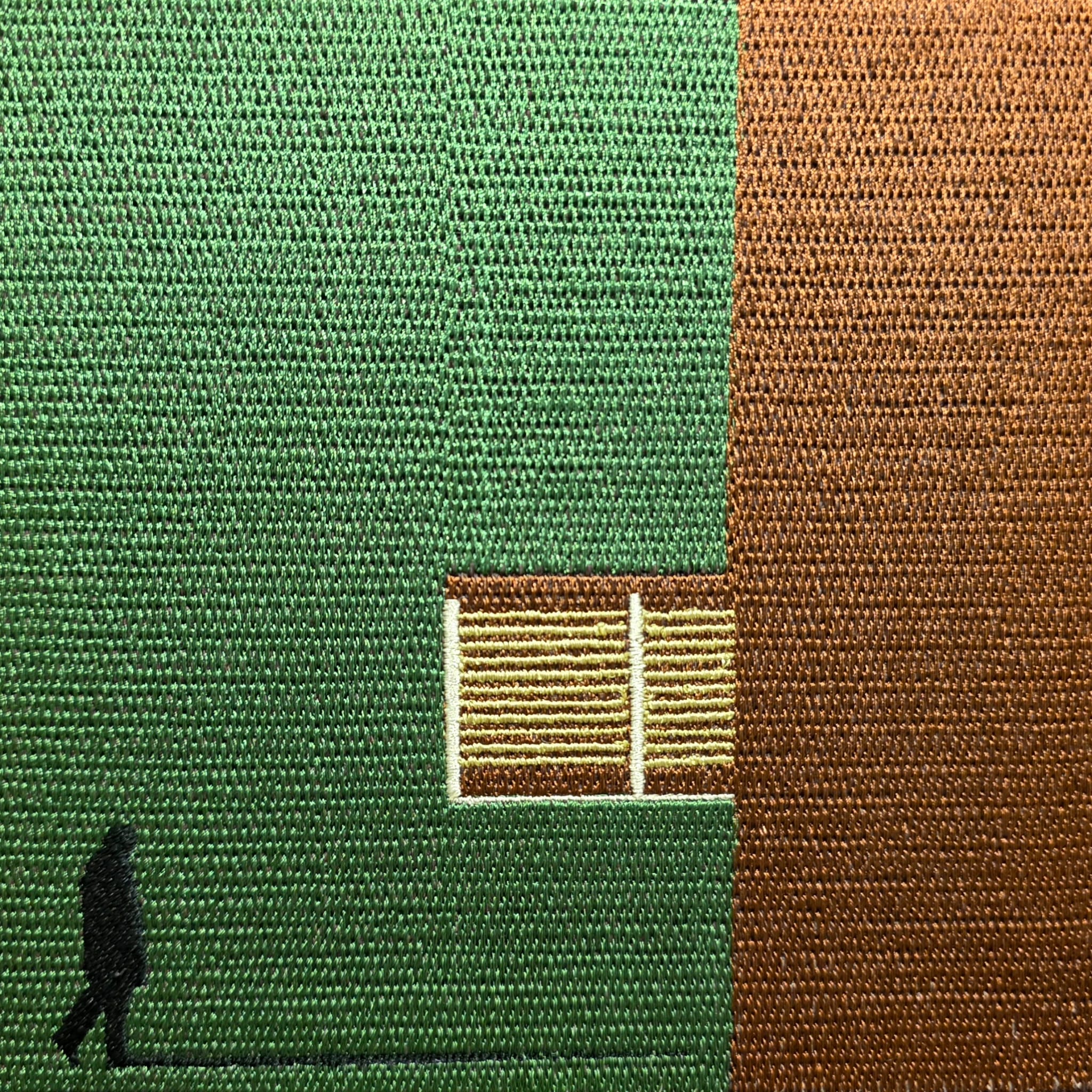 Detailed embroidery on brown canvas tote featuring minimalist green geometric architectural art design