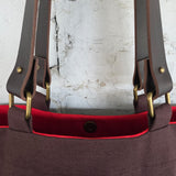 Close-up of brown tote bag with detachable leather handles and brass hardware details