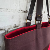 Open brown tote bag showing bright red lining and magnetic snap closure