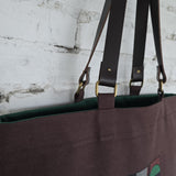 Brown bag with green interior against a textured white wall