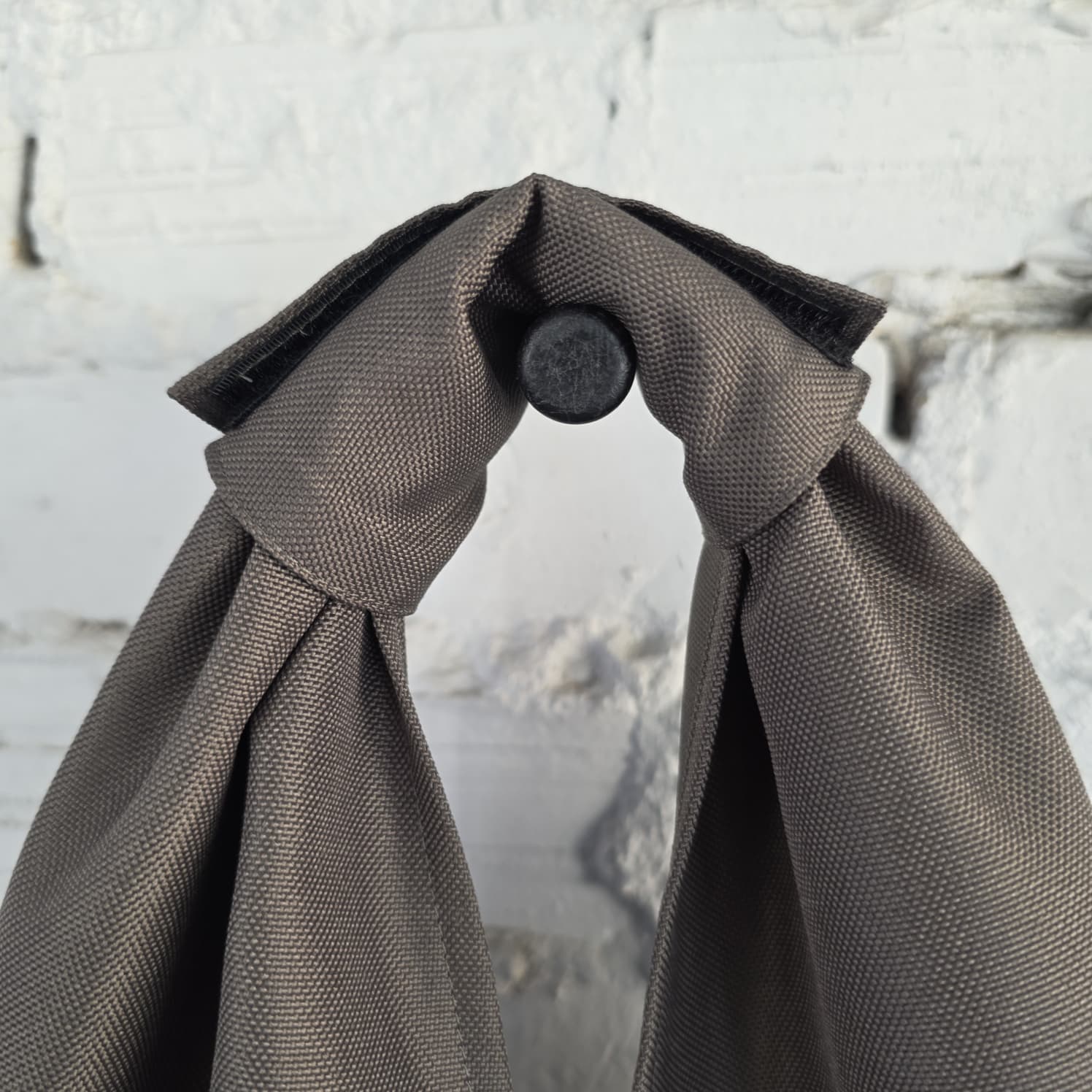 Close-up of wide integrated fabric handle on khaki hobo bag