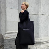 Smiling woman with large cotton tote bag “HAPPY DAY”
